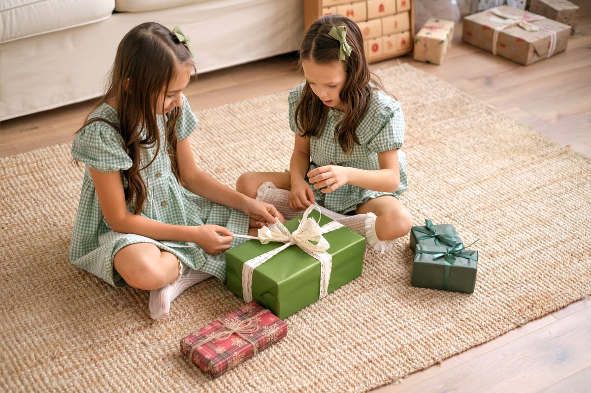 Children untying a ribbon on a large wrapped gift box